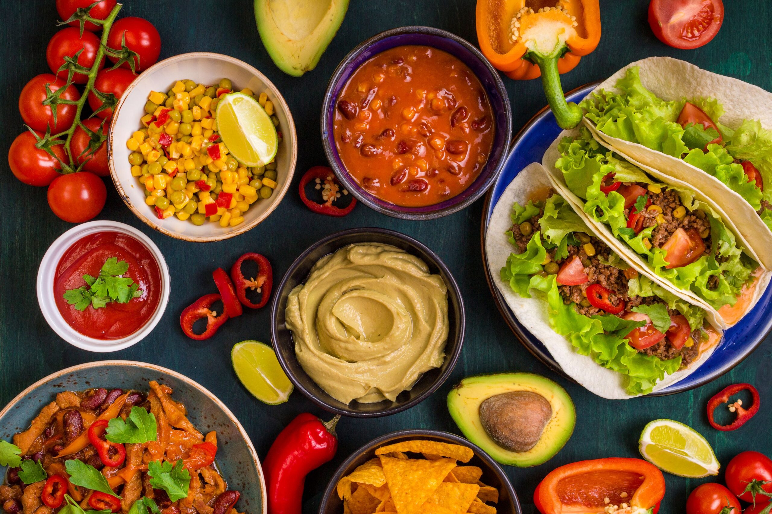 Mixed mexican food. Party food. Guacamole, nachos, fajita, meat tacos, salsa, peppers, tomatoes on a wooden table. Top view. Tex-mex cuisine. Assorted appetizers. Cuisine of Mexico